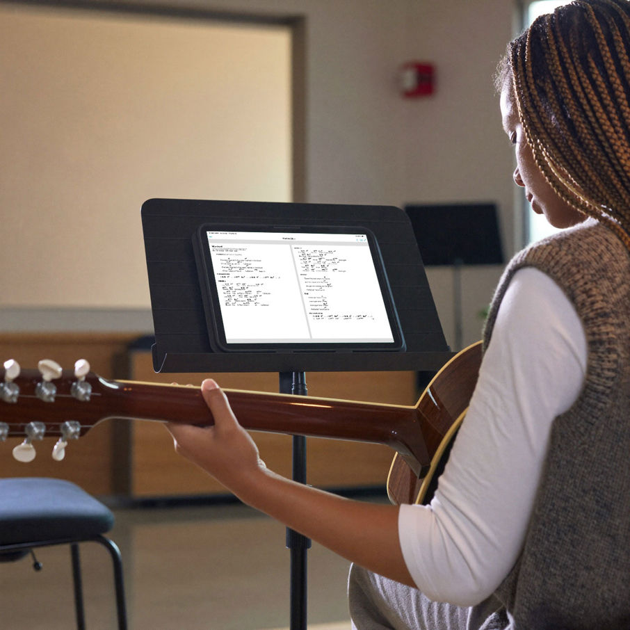 A worship musician reading a chord chart in the Charts app on an iPad during rehearsal
