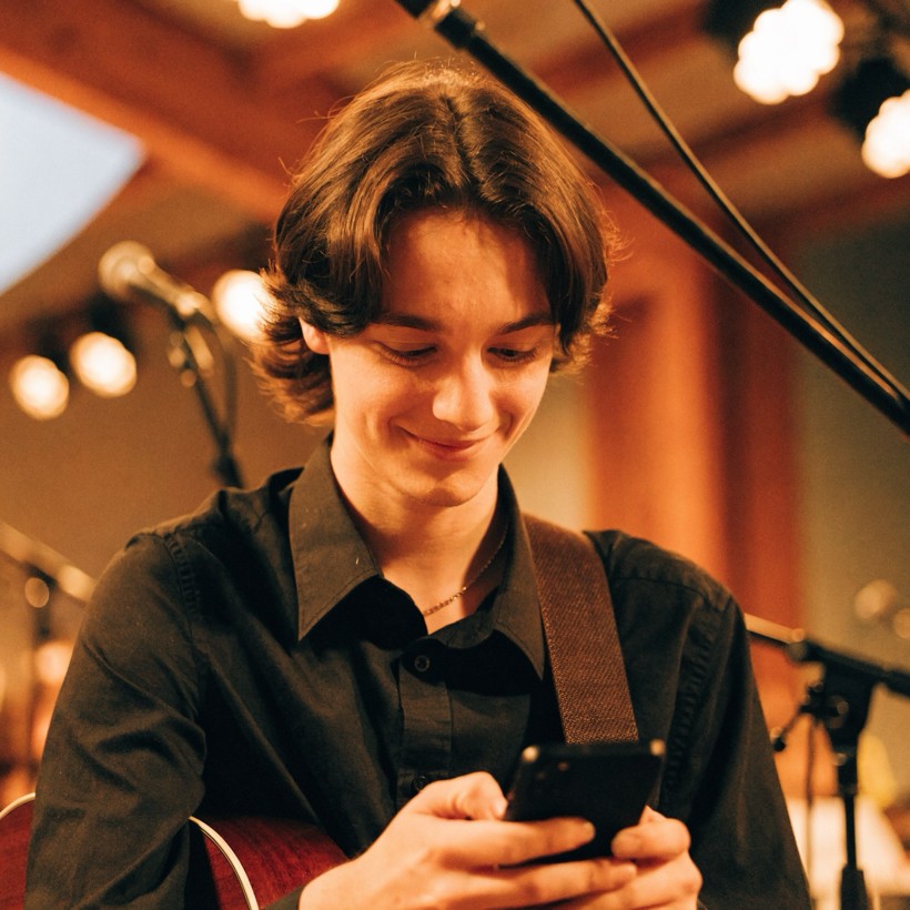 Um músico do louvor conferindo no celular um lembrete do culto